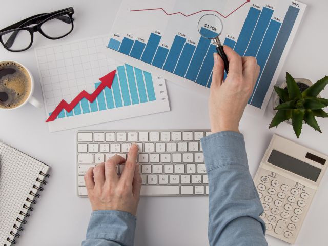 top-view-office-desk-with-growth-chart-hands-with-keyboard